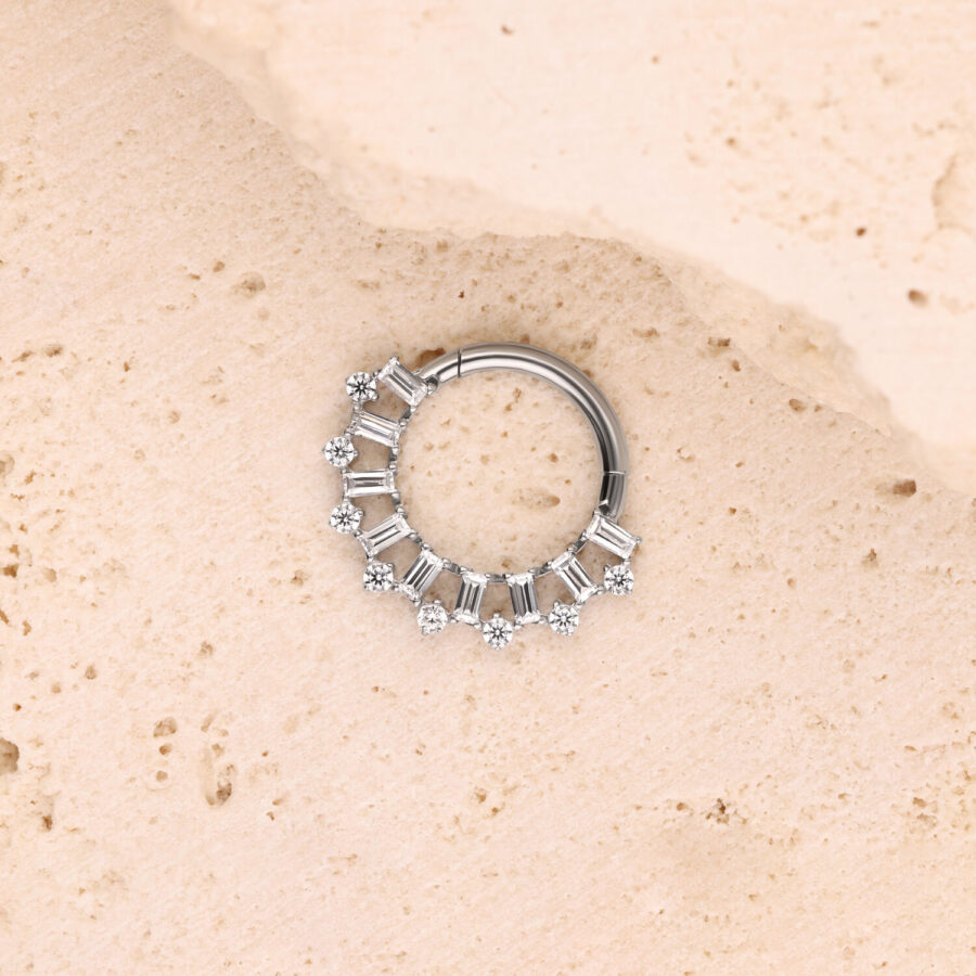 Silberner Piercingring mit Kristallen auf heller Steinoberfläche