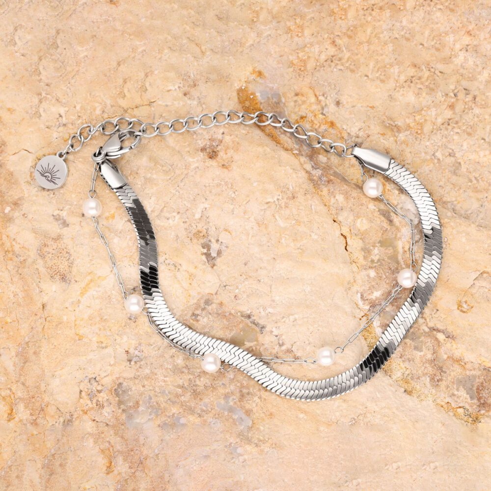 Silbernes Armband mit Perlen und Kettenverbindung auf sandigem Hintergrund