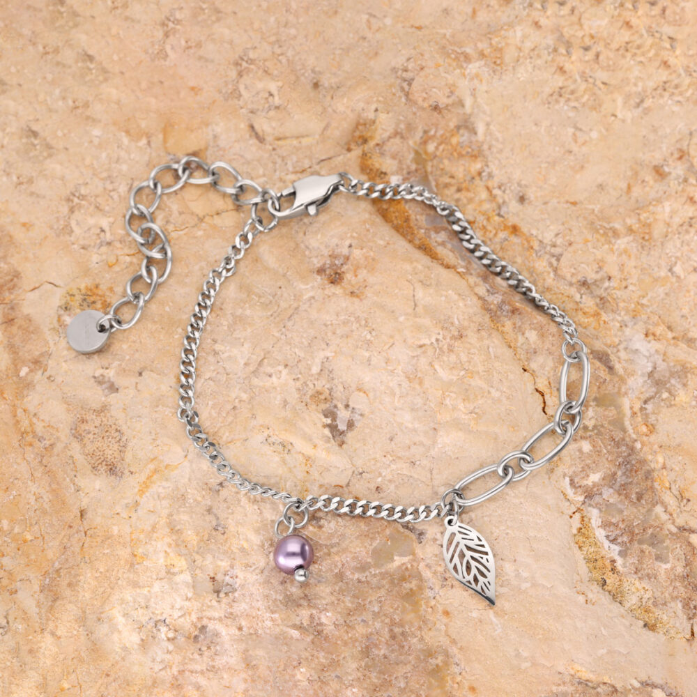 Feines silbernes Armband mit Blatt- und lila Perlenanhänger auf steinigem Hintergrund