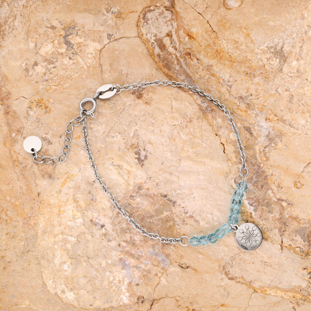 Silberarmband mit blauen Kristallen und Blumenanhänger auf Steinuntergrund