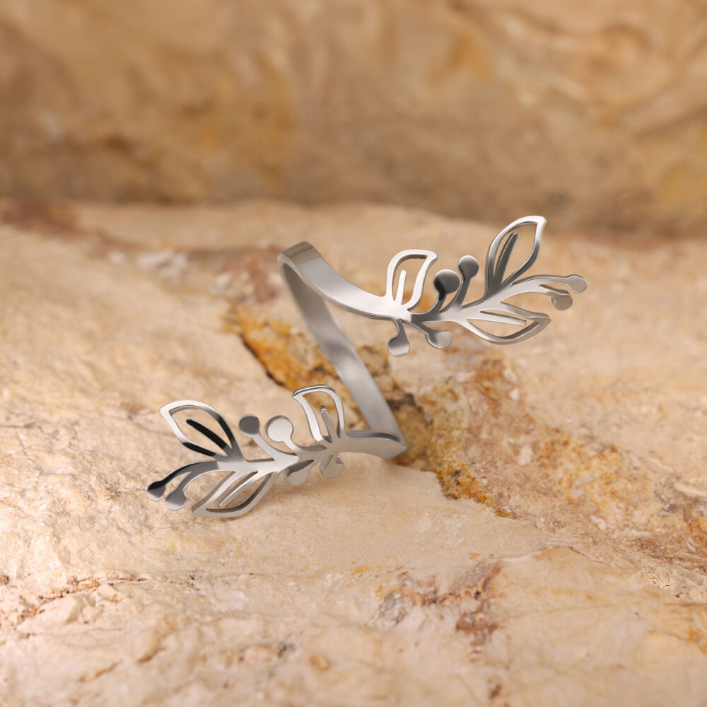 Silberner Ring mit filigranem Blattmotiv auf beigem Steinuntergrund