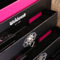 Nahaufnahme des Wildcat Adventskalenders 2026 mit schwarzer und pinker Verpackung, Schmuckstück in einer Schublade.