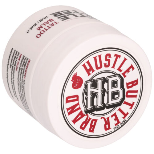 Weiße Dose mit Hustle Butter Branding und rotem Schriftzug, auf der Seite liegend