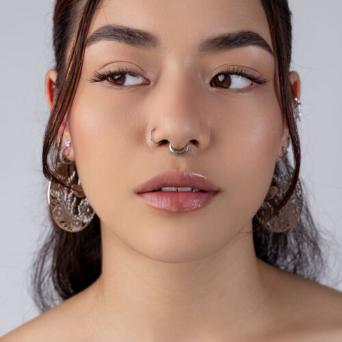 Nahaufnahme eines Gesichts mit silbernem Septum Clicker und großen Ohrringen
