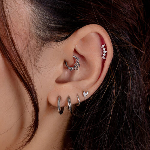 Ohr mit mehreren silbernen Piercings, inkl. Kristallkette und Ringe