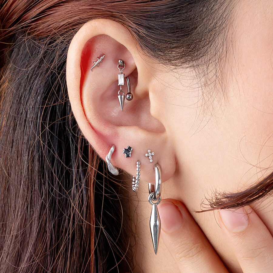 Ohr mit mehreren silbernen und schwarzen Piercings, Rook und Helix