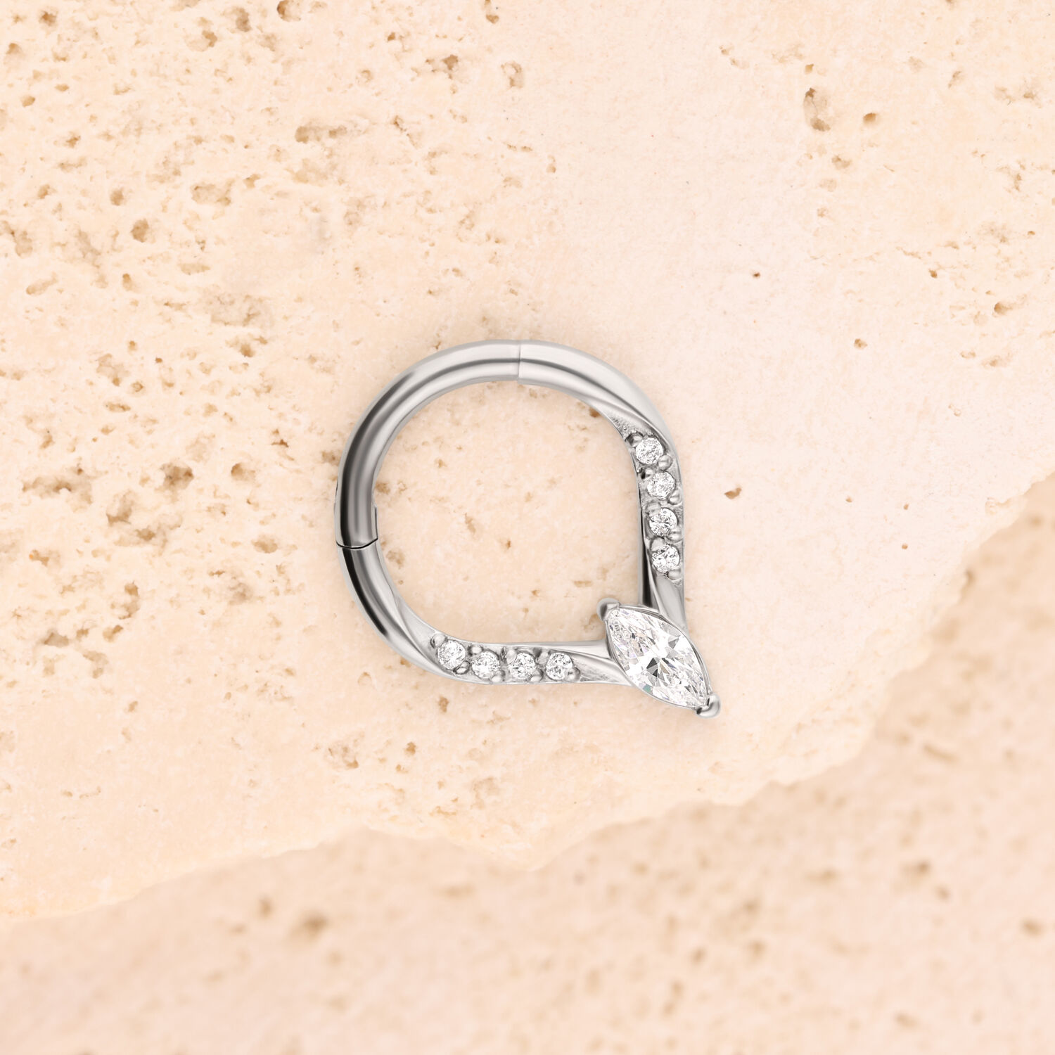 Silberner Crystal Teardrop Clicker Silberner Piercingring mit Kristallen auf beige strukturiertem Hintergrund
