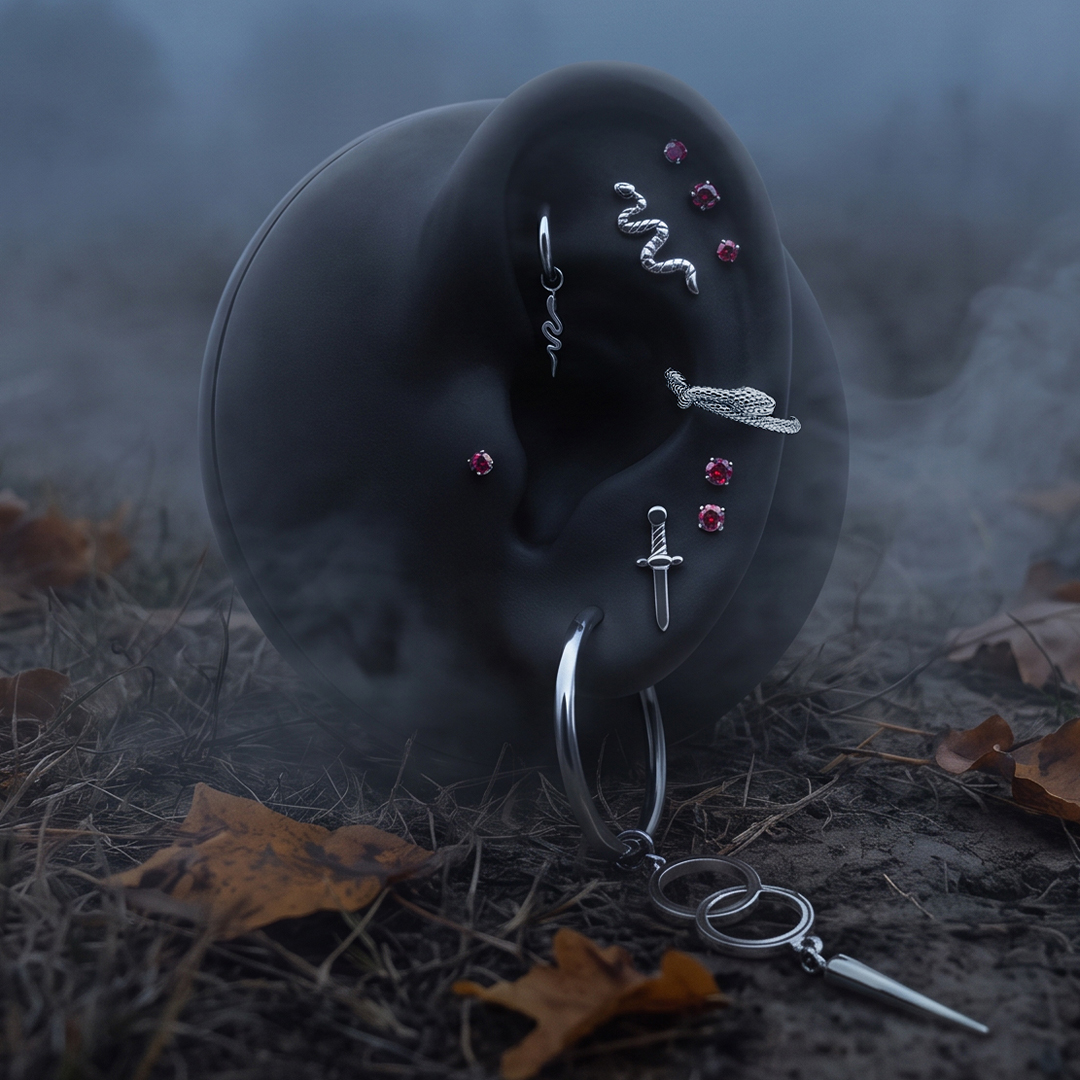 Schwarze Ohrattrappe mit silbernen Schlangen- und Dolchsteckern, im Nebel auf Laubboden