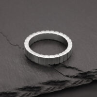Silberner Ring aus Chirurgenstahl auf grauem Steinuntergrund