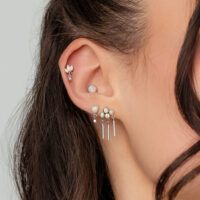 Nahaufnahme eines Ohrs mit mehreren Piercings, darunter ein weißgoldener Opal Statement Aufsatz