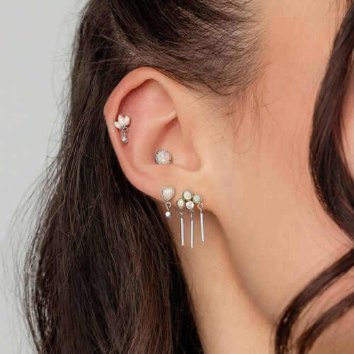 Nahaufnahme eines Ohrs mit mehreren Piercings, darunter ein weißgoldener Opal Statement Aufsatz