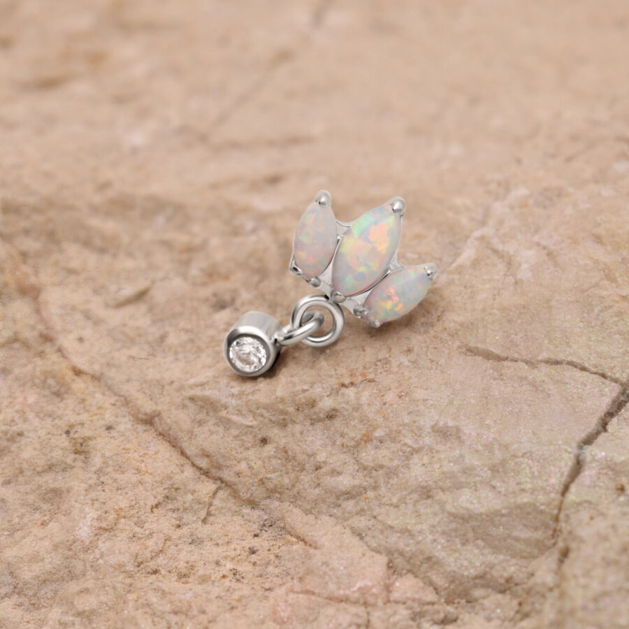 Lotusförmiger Opal-Piercingaufsatz aus Titan auf einem steinigen Hintergrund
