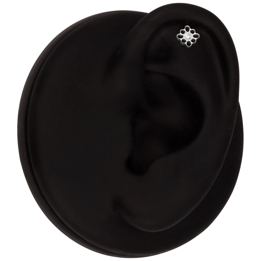 Schwarzes Ohrmodell mit weißgoldenem Blumen-Piercing im Helix-Bereich